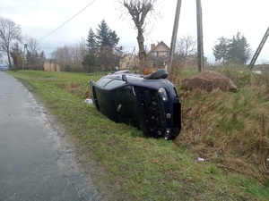 granatowy samochód leży na boku w rowie