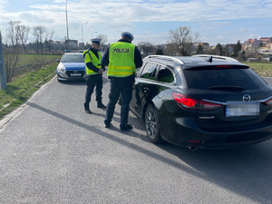 Dwóch policjantów stoi przy zatrzymanym do kontroli samochodzie