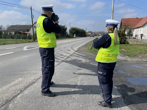 Policjant stoi przy drodze i mierzy prędkość