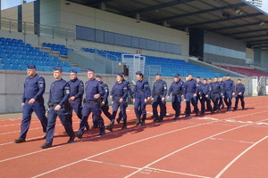 policjanci maszerują w dwuszeregu po płycie stadionu