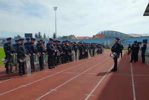 policjanci stoją w dwuszeregu na płycie stadionu ubrani w sprzęt ochrony osobistej