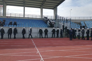 policjanci ubrani w sprzęt ochrony osobistej wchodzą na trybuny stadionu