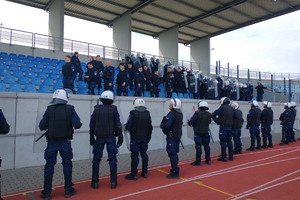 policjanci ubrani w sprzęt ochrony osobistej przemieszczają się po trybunach stadionu