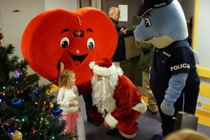 Polfin wraz z maskotką krwiodawstwa i Mikołajem rozmawiającym z dzieckiem.
