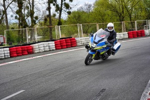 Jeden policjant jedzie motocyklem po torze wyścigowym