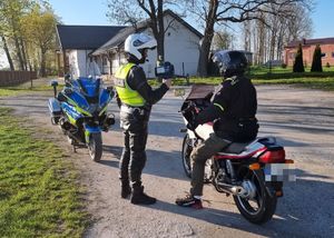 policjant pokazuje motocykliście wynik z pomiaru miernika prędkości