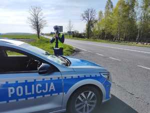 policjant dokonuje pomiaru miernikiem prędkości stojąc obok radiowozu