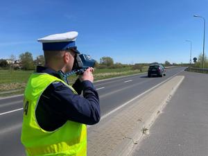 Policjant mierzy prędkość pojazdów przy drodze