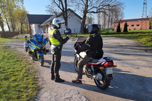 Policjant pokazuje wynik z miernika prędkości zatrzymanemu do kontroli motocykliście