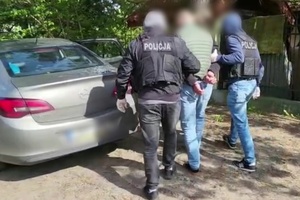 Policjanci prowadzą zatrzymanego mężczyznę