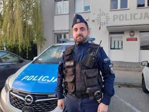 umundurowany policjant stoi przed radiowozem