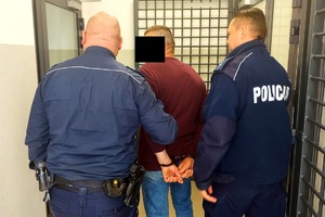 Policjanci prowadzą zatrzymanego mężczynzę