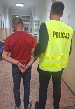 Policjant prowadzi zatrzymanego mężczyznę