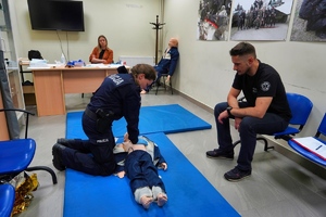 Policjantka przeprowadza resuscytację na manekinie leżącym na ziemi