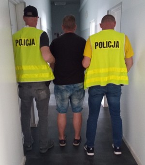 Policjanci w kamizelkach prowadzą podejrzanego