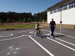 Policjant, a obok dziecko jadące na rowerze