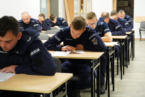 policjanci siedzą w ławkach i rozwiązują test