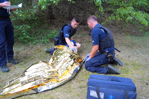 dwaj policjanci prezentują udzielanie pierwszej pomocy na manekinie