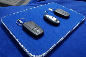 trzy kluczyki do pojazdów leżą na niebieskiej podstawce