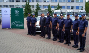 wspólne zdjęcie Komendanta i Prezesa funduszu z policjantami na tle nowych radiowozów