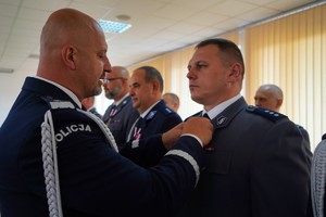 Komendant przypina medal do munduru policjanta