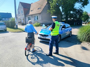 Policjant kontroluje rowerzystę przy przejściu dla pieszych