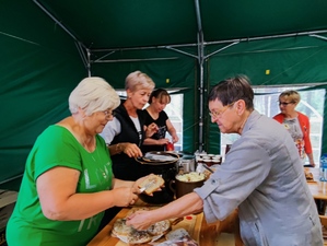 Grupa osób przygotowujących posiłek, chleb ze smalcem.
