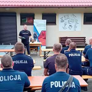 Uczestnicy szkolenia siedzą w ławkach i słuchają wykładowcy