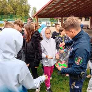 Policjant przekazuje odblaski obserwatorom pokazów