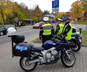 Policjanci przy motocyklu na cmentarzu.