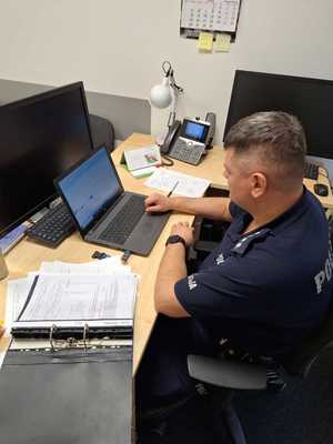 Policjant siedzi przed laptopem i prowadzi szkolenie on-line