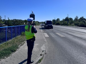 Policjantka stoi na chodniku i mierzy prędkość samochodu