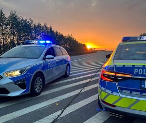 Dwa radiowozy stoją na pasie autostrady o świcie