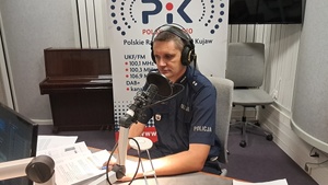 policjant siedzi w studiu i ma założone na głowie słuchawki