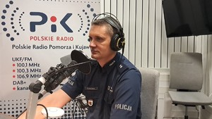 policjant siedzi w studiu i ma założone na głowie słuchawki