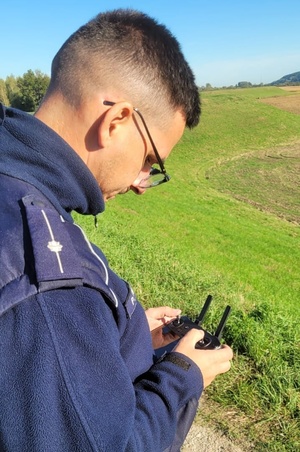 Policjant trzyma w dłoniach pilot do drona