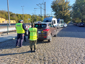 Funkcjonariusze kontrolują kierowcę i samochód z napisem taxi