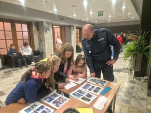 Policjant pokazuje nastolatkom ułożone na stole zdjęcia