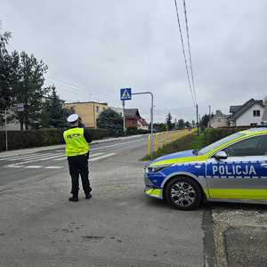 Policjant stoi przy drodze i mierzy prędkość podjazdów