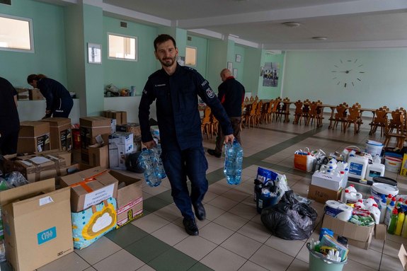 Policjant niesie baniaki z pitną wodą