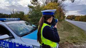 Policjant stoi przy drodze i mierzy prędkość