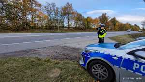 Policjant stoi przy drodze i mierzy prędkość