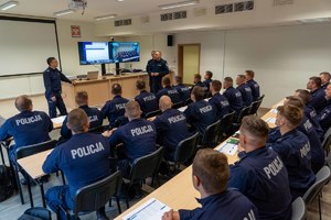 Komendant przemawia do policjantów siedzących przy stołach