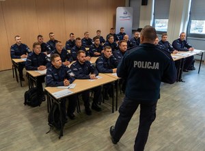 Komendant przemawia do policjantów siedzących przy stołach