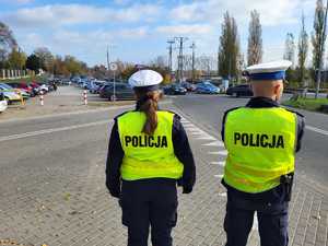 Policjanci stoją przy skrzyżowaniu i obserwują ruch drogowy