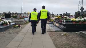 Dwóch policjantów patroluje teren cmentarza