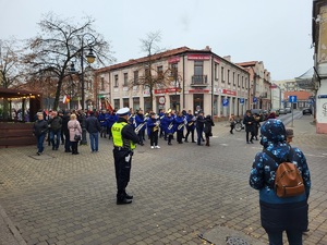 Policjant stoi przy drodze i obserwuje ruch zapewniając bezpieczeństwo uczestników marszu