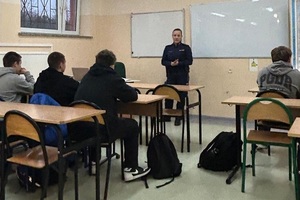 Policjantka przemawia do uczniów siedzących w szkolnych ławkach