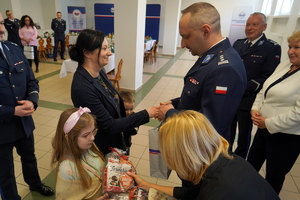 Komendant rozmawia z rodzinami poległych policjantów i składa im życzenia, wręczając upominki