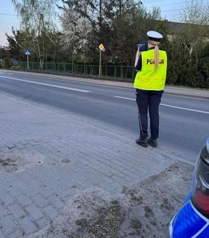 policjantka stoi przy ulicy i mierzy miernikiem prędkości